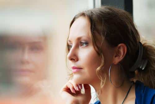 Woman looking out window with question look on her face.